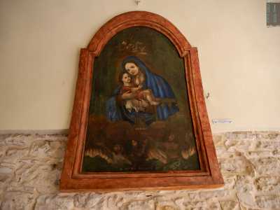 Con Ges� tra le braccia, tiene in mano lo scapolare: due rettangolini di stoffa raffiguranti Maria con il bambino e il cuore di Cristo. Sotto il mezzobusto, delle anime tra le fiamme del Purgatorio si rivolgono a lei
